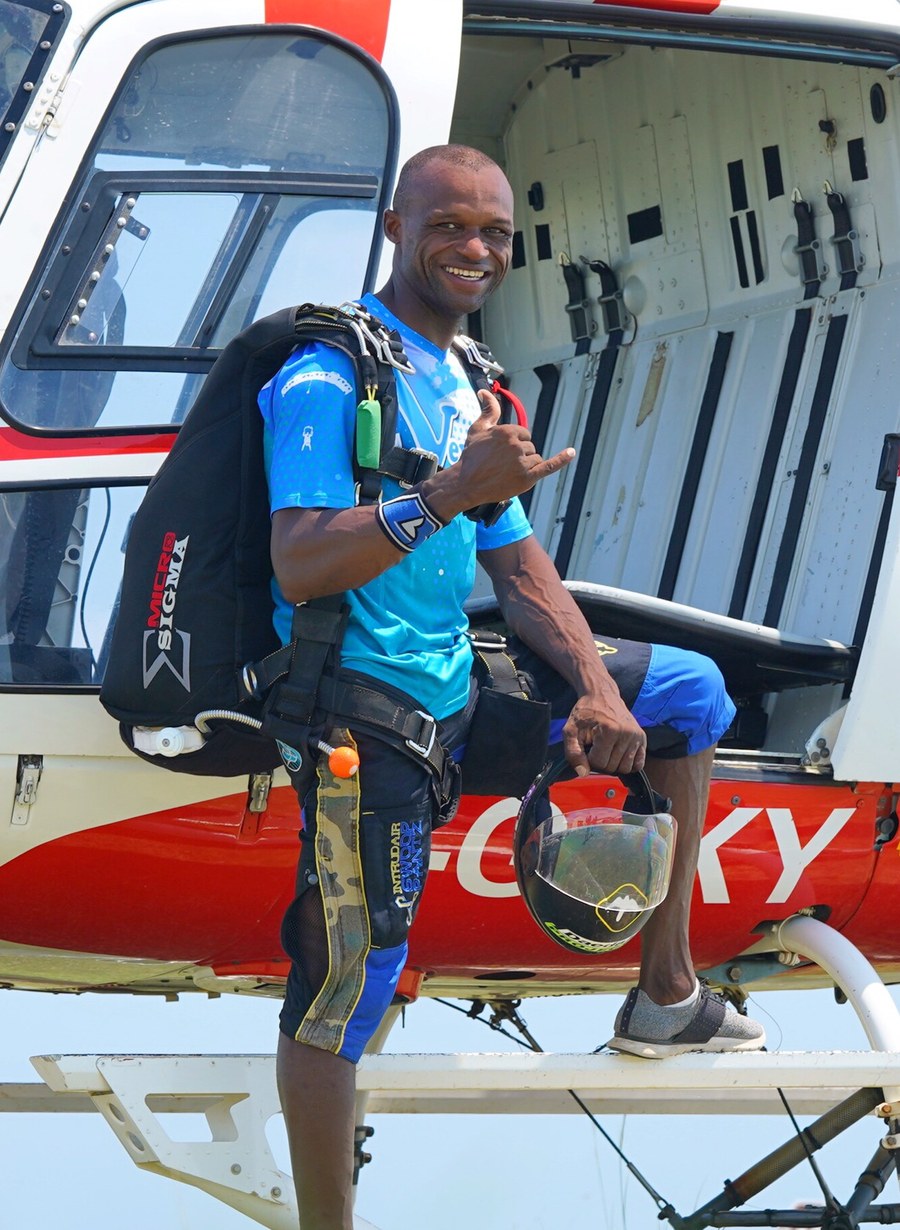 Anli, gérant et moniteur tandem de Vewuha Parachutisme, en tenue de saut devant l'hélicoptère